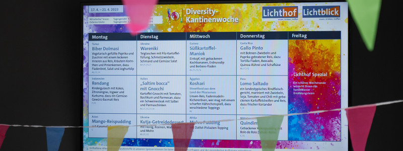 Bildschirm in der Kantine mit dem Speiseplan im bunten Layout des Diversity Days