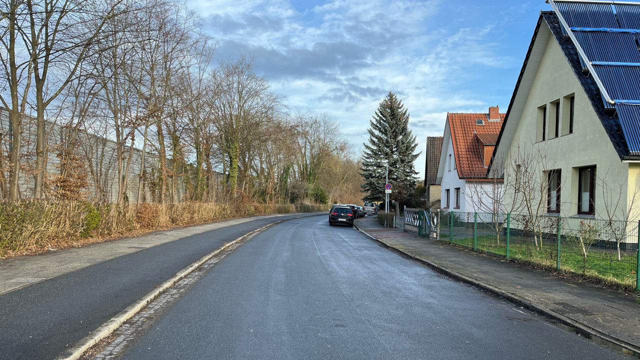 Straße mit viel Asphalt und Gebäude auf der rechten Seite.