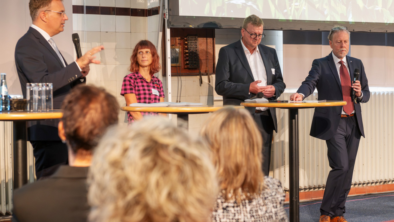 Vier Personen stehen auf der Bühne und diskutieren.