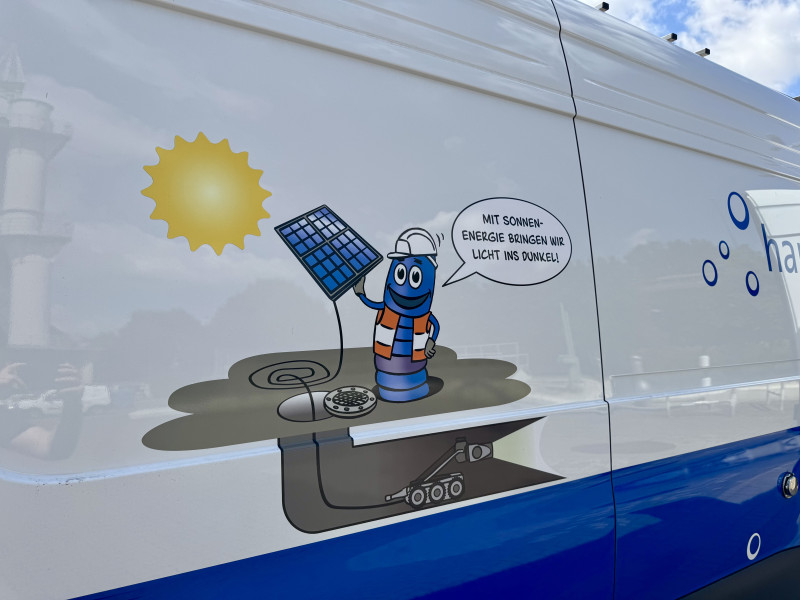 Grafik auf einem Fahrzug mit Solarmodul mit der Aufschrift "Mit Sonnenenergie bringen wir Licht ins Dunkel".