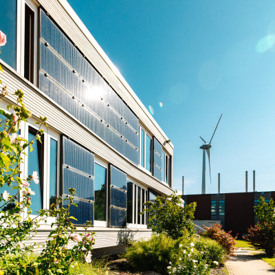 Ansicht der Gebäudefront in Seehausen mit Solarpanels und vielen blühenden Blumen