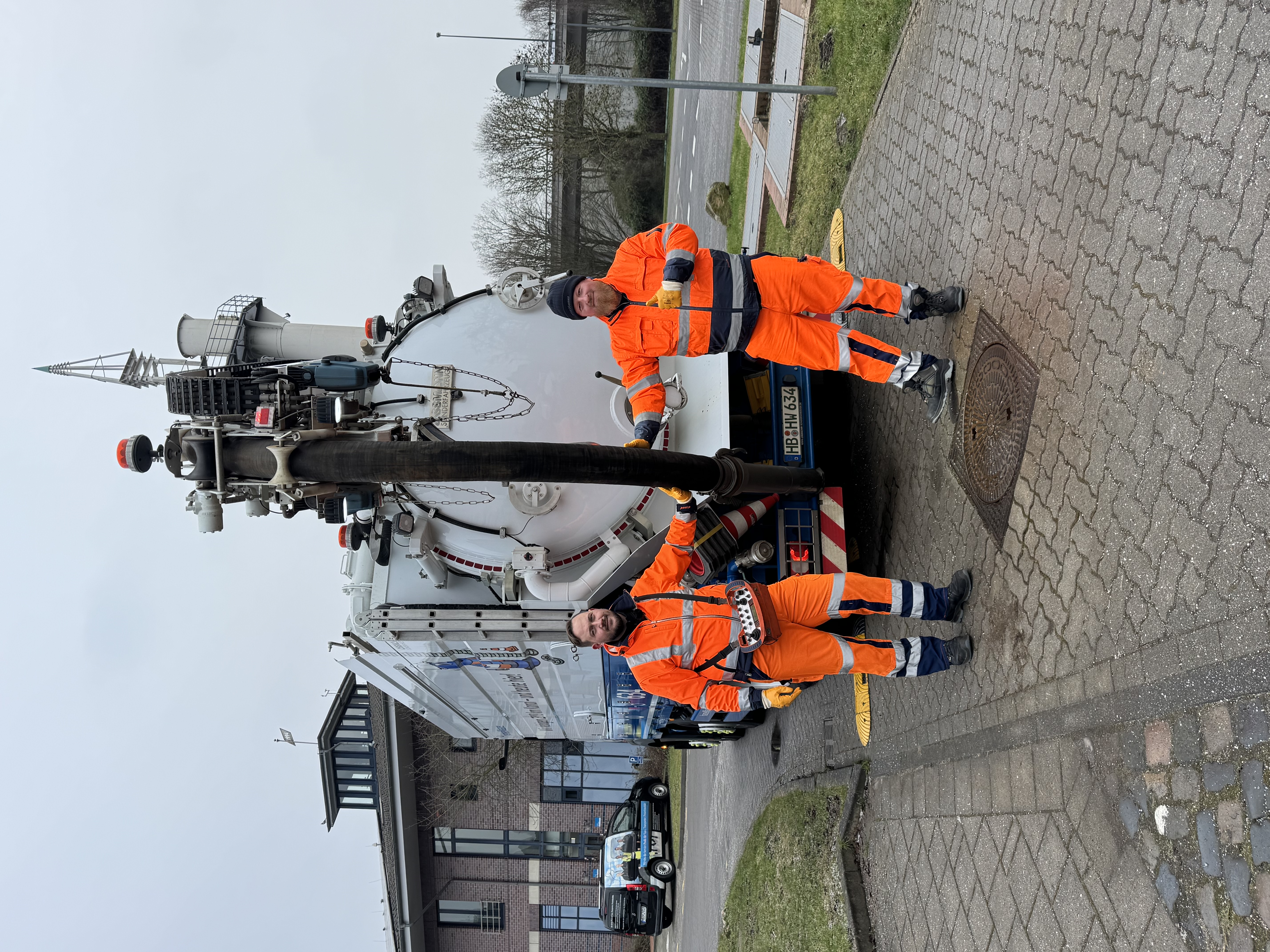 Zwei Mitarbeiter von hanseWasser posieren vor einem Spülwagen