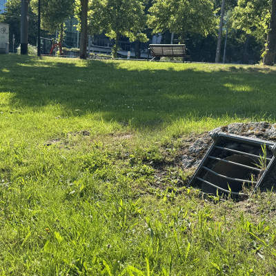 Wasserauslass an einer Mulde in Mitten einer grünen Wiese