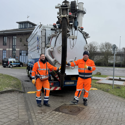 Zwei Mitarbeiter von hanseWasser posieren vor einem Spülwagen